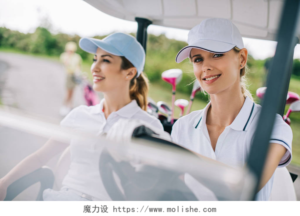 两个女人开着小车高尔夫球场骑高尔夫球车帽中微笑的女高尔夫球手肖像